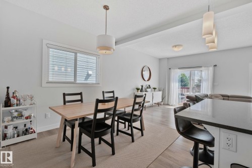 Open-concept dining area featuring wood-finish flooring, a contemporary pendant light fixture, and a large window with horizontal blinds - 249 39A Avenue, Edmonton, AB - Indoor Photo Showing Dining Room