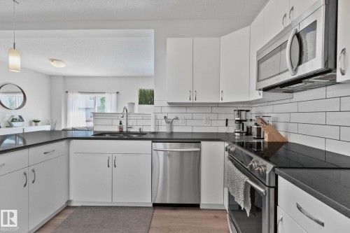 Modern kitchen featuring white cabinetry, dark countertops, and stainless steel appliances - 249 39A Avenue, Edmonton, AB - Indoor Photo Showing Kitchen