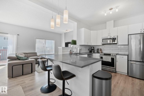 Modern kitchen featuring white cabinetry, subway tile backsplash, stainless steel appliances, and a gray countertop island with pendant lighting - 249 39A Avenue, Edmonton, AB - Indoor Photo Showing Kitchen With Double Sink With Upgraded Kitchen