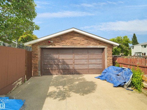 Detached garage featuring a paneled door, stone-finish siding, and a gabled roofline - 15603 122 Street Nw, Edmonton, AB - Outdoor
