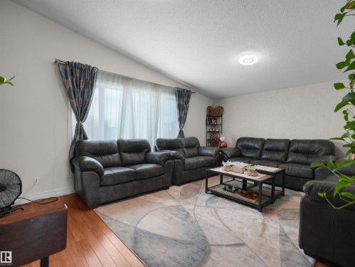 Living area featuring wood-finish flooring and a central area rug - 15603 122 Street Nw, Edmonton, AB - Indoor Photo Showing Living Room