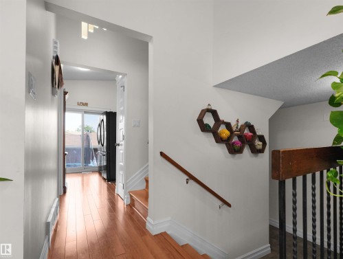 Hardwood-finish flooring extending from the hallway, leading to a glass sliding door - 15603 122 Street Nw, Edmonton, AB - Indoor Photo Showing Other Room