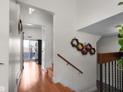 Hardwood-finish flooring extending from the hallway, leading to a glass sliding door - 