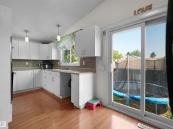 Kitchen featuring white cabinetry, wood-finish flooring, light-colored countertops, a tile backsplash, and stainless steel appliances - 