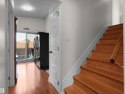 Hardwood staircase with matching handrail, white trim, and light wall finishes - 15603 122 Street Nw, Edmonton, AB - Indoor Photo Showing Other Room