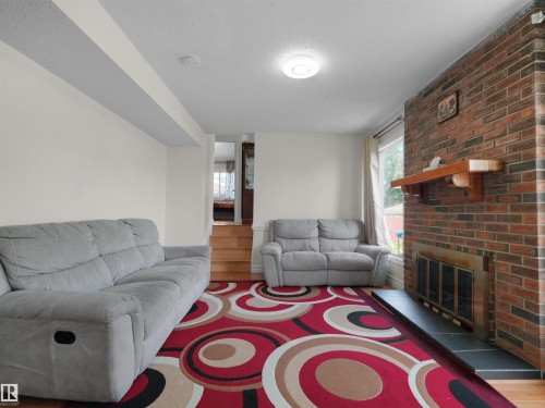 Brick-faced fireplace with a stone hearth and a wood mantle - 15603 122 Street Nw, Edmonton, AB - Indoor Photo Showing Living Room With Fireplace