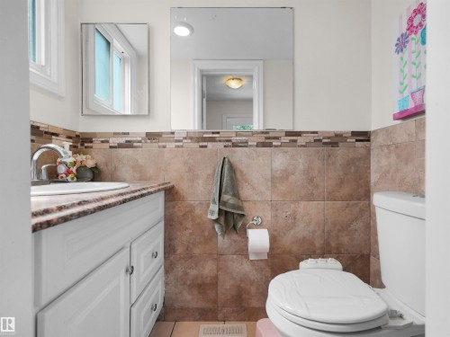 Bathroom vanity with a white basin sink and chrome faucet, set against a tiled wall with a decorative mosaic accent - 15603 122 Street Nw, Edmonton, AB - Indoor Photo Showing Bathroom