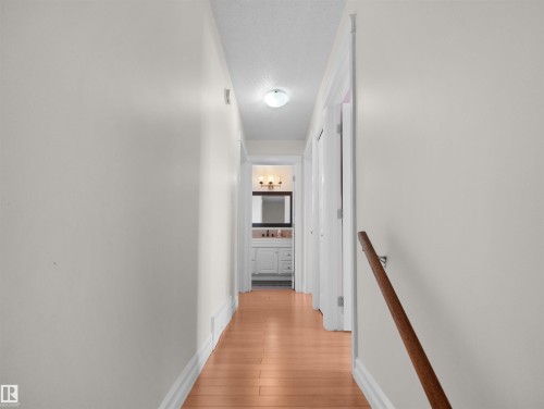 Hallway featuring wood-finish flooring and a wall-mounted handrail - 15603 122 Street Nw, Edmonton, AB - Indoor Photo Showing Other Room