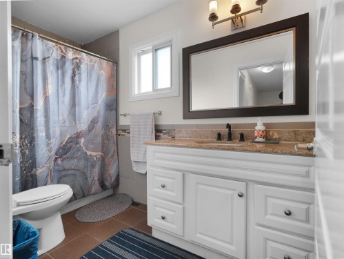 Bathroom featuring a white vanity with panel cabinetry and a stone countertop - 15603 122 Street Nw, Edmonton, AB - Indoor Photo Showing Bathroom