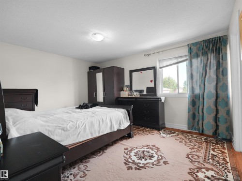 Bright bedroom featuring a single window with blinds and patterned curtains - 15603 122 Street Nw, Edmonton, AB - Indoor Photo Showing Bedroom