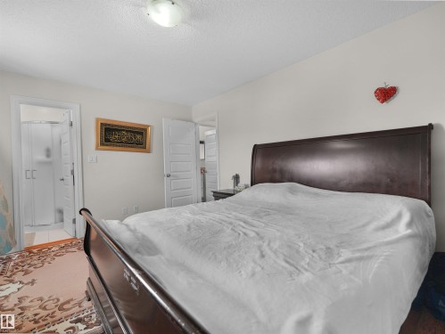 Bedroom featuring light-toned walls, a flush-mount ceiling light, and an open doorway revealing a shower enclosure - 15603 122 Street Nw, Edmonton, AB - Indoor Photo Showing Bedroom