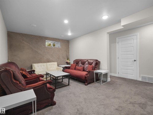 Finished lower level featuring recessed lighting, plush grey carpeting, a textured accent wall, and a five-panel interior door - 15603 122 Street Nw, Edmonton, AB - Indoor