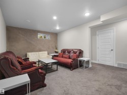 Finished lower level featuring recessed lighting, plush grey carpeting, a textured accent wall, and a five-panel interior door - 