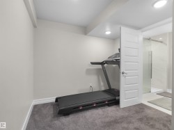 Carpeted room with recessed lighting and a five-panel interior door opening to a bathroom with a glass-enclosed shower featuring white tile - 