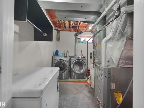 Laundry area featuring a built-in hanging rod, exposed ceiling joists, and utility access - 15603 122 Street Nw, Edmonton, AB - Indoor Photo Showing Laundry Room