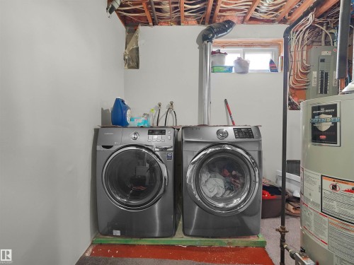 Dedicated laundry area featuring a front-loading washer and dryer set, water heater, and exposed ceiling joists - 15603 122 Street Nw, Edmonton, AB - Indoor Photo Showing Laundry Room