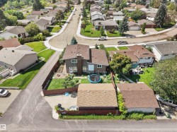 Two-story residence with a brown shingle roof, featuring a private fenced backyard with a patio area and mature landscaping - 
