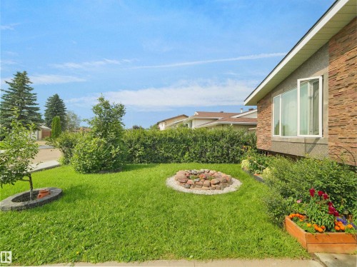 Front exterior featuring a stone accent wall, large picture window, and a planted wooden box - 15603 122 Street Nw, Edmonton, AB - Outdoor