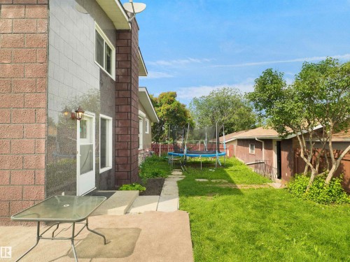 Expansive rear yard featuring green lawn space, a concrete patio, and a separate structure - 15603 122 Street Nw, Edmonton, AB - Outdoor With Exterior