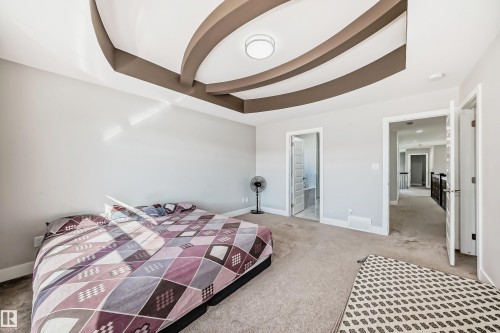 Bedroom featuring a tray ceiling with decorative brown accents, light gray wall paint, and light-colored carpet flooring - 2464 15 Avenue Nw, Edmonton, AB - Indoor Photo Showing Bedroom
