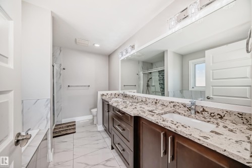 Bathroom featuring a double vanity with stone countertops, integrated rectangular sinks, and dark wood-finish cabinetry - 2464 15 Avenue Nw, Edmonton, AB - Indoor Photo Showing Bathroom