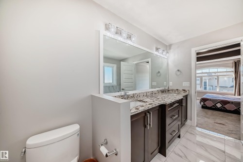 Bathroom featuring a double vanity with stone-finish countertop, dark wood cabinetry, dual undermount sinks, and contemporary wall-mounted light fixtures - 2464 15 Avenue Nw, Edmonton, AB - Indoor Photo Showing Bathroom
