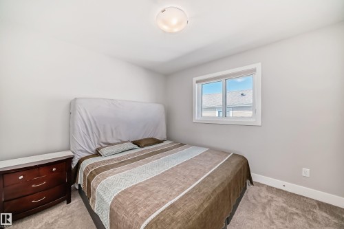 Well-lit bedroom featuring light gray walls, white trim, and a window with white casing - 2464 15 Avenue Nw, Edmonton, AB - Indoor Photo Showing Bedroom