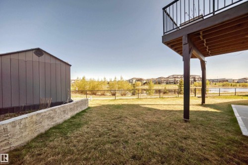 Expansive backyard featuring a metal storage shed, a stucco retaining wall, and a raised wooden deck with black metal railings - 2464 15 Avenue Nw, Edmonton, AB - Outdoor