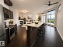 Open-concept living space featuring wood-finish flooring, a kitchen island with seating, a built-in fireplace, dark cabinetry, and expansive windows - #412 9503 101 Av Nw, Edmonton, AB  - Indoor Photo Showing Kitchen With Upgraded Kitchen 