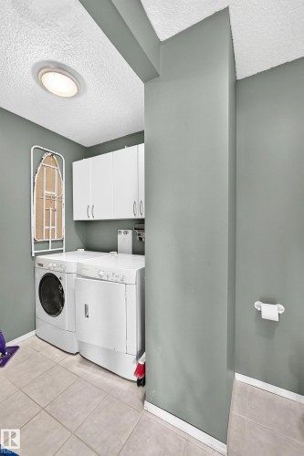 Dedicated laundry area with tile flooring and overhead white cabinetry - 1116 39 Street Nw, Edmonton, AB - Indoor Photo Showing Laundry Room