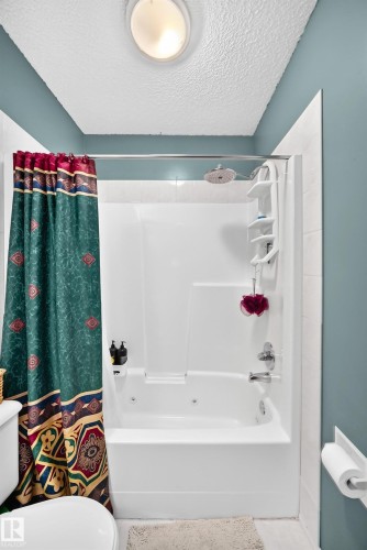White bathtub with integrated wall surround, chrome fixtures, and a ceiling-mounted light fixture - 1116 39 Street Nw, Edmonton, AB - Indoor Photo Showing Bathroom