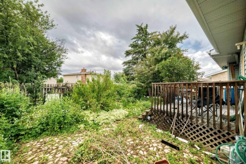 Spacious backyard featuring a wooden deck with railing, lattice skirting, and a paver stone patio area - 1116 39 Street Nw, Edmonton, AB - Outdoor