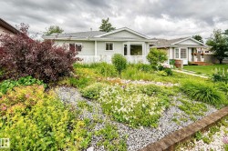 Front yard with a variety of plantings, decorative gravel, and a low retaining wall - 