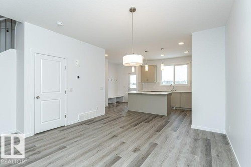 Open-concept living space with wood-finish flooring, a contemporary kitchen, and a central island - 6269 175A Avenue Nw, Edmonton, AB - Indoor Photo Showing Kitchen