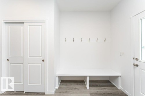 Entryway featuring a built-in bench, wall-mounted coat hooks, and durable wood-finish flooring - 6269 175A Avenue Nw, Edmonton, AB - Indoor
