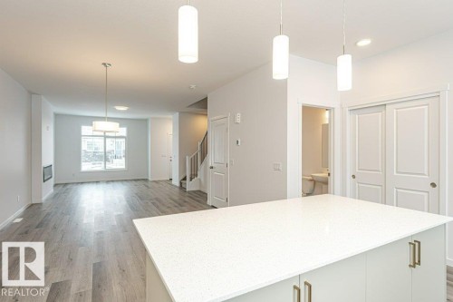 Spacious interior featuring wood-finish flooring, a contemporary island with a light-toned countertop, and modern pendant lighting - 6269 175A Avenue Nw, Edmonton, AB - Indoor