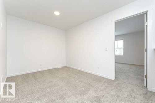 Carpeted interior room featuring a recessed ceiling light, white baseboards, and a doorway opening to another room with a window - 6269 175A Avenue Nw, Edmonton, AB - Indoor Photo Showing Other Room