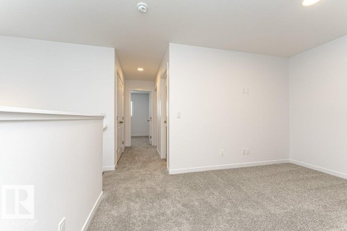 Carpeted landing area featuring white walls, white trim, and a partial wall with a cap - 6269 175A Avenue Nw, Edmonton, AB - Indoor Photo Showing Other Room