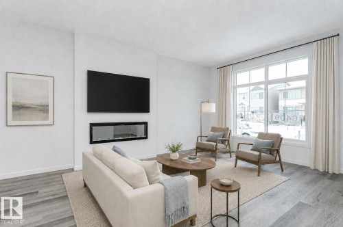 Bright living area featuring a built-in linear fireplace, large picture window with white trim, and wood-finish flooring - 6269 175A Avenue Nw, Edmonton, AB - Indoor Photo Showing Living Room With Fireplace