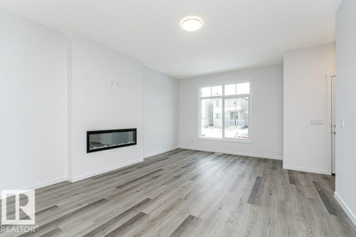 Living area featuring wood-finish flooring and a linear electric fireplace - 6269 175A Avenue Nw, Edmonton, AB - Indoor With Fireplace