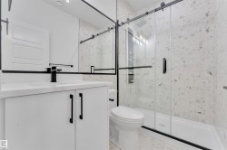 Modern bathroom featuring a white vanity with a rectangular undermount sink, matte black faucet, and coordinating cabinet hardware - 