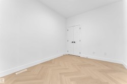Room with light wood-finish herringbone flooring, white walls, and white baseboards - 