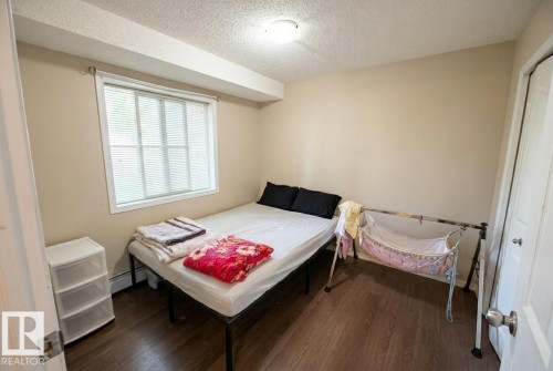 Bedroom featuring wood-finish flooring, a window with horizontal blinds, and neutral-toned walls - #107 530 Watt Bv Sw, Edmonton, AB - Indoor Photo Showing Bedroom