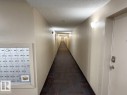 Corridor featuring wall-mounted sconces, textured walls, and patterned carpet flooring - #107 530 Watt Bv Sw, Edmonton, AB  - Indoor Photo Showing Other Room 