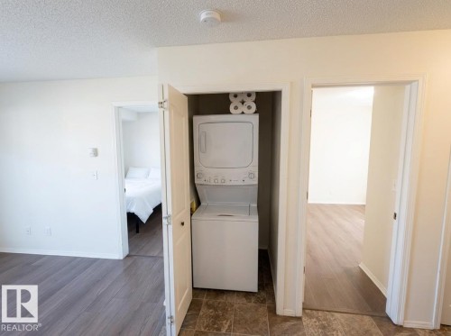 Dedicated laundry closet featuring a stacked washer and dryer - #107 530 Watt Bv Sw, Edmonton, AB - Indoor Photo Showing Laundry Room
