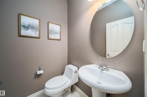 Pedestal sink with chrome faucet and oval wall-mounted mirror - 11342 79 Avenue, Edmonton, AB - Indoor Photo Showing Bathroom
