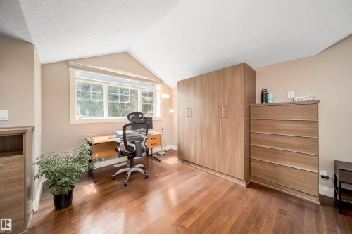 Room featuring hardwood flooring, sloped ceiling, and a prominent window - 11342 79 Avenue, Edmonton, AB - Indoor