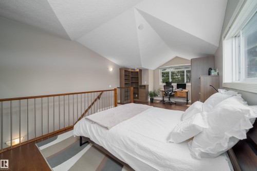 Spacious loft area featuring sloped ceilings, wood-finish flooring, and a contemporary railing with metal spindles - 11342 79 Avenue, Edmonton, AB - Indoor Photo Showing Bedroom