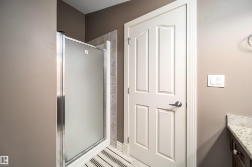 Shower enclosure with frosted glass panels, tile surround, and a white paneled door - 11342 79 Avenue, Edmonton, AB - Indoor