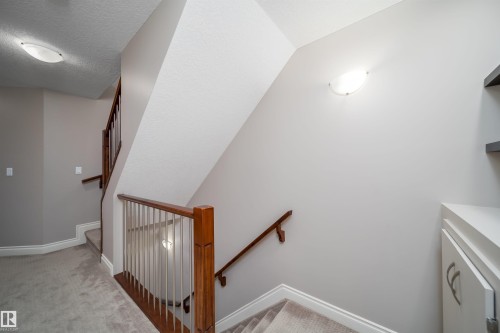 Carpeted staircase with wood handrails and white balusters - 11342 79 Avenue, Edmonton, AB - Indoor Photo Showing Other Room